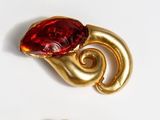 a gold brooch with a red stone in it