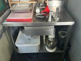 a small kitchen with a stainless steel table and a refrigerator