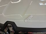 the front end of a white car with a sticker on it ' s hood