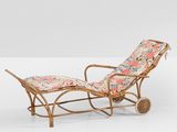 a pair of rattan loungers with floral cushions and wheels