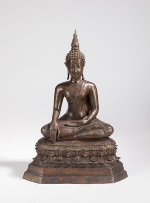 une statue en bronze représentant un Bouddha assis sur un rocher