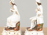 two figurines of a woman and a man sitting on a bench