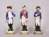three figurines of men dressed in uniforms of different colors and sizes