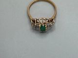 an image of a gold ring with a green stone and diamonds