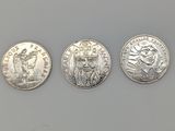 trois types différents de pièces d'argent sur une surface blanche