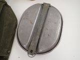 a metal container with a handle on a table next to a bag
