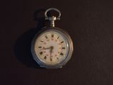 a silver pocket watch with a white face on a black surface
