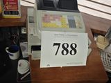 une photo d'une caisse enregistreuse posée sur un bureau devant une fenêtre