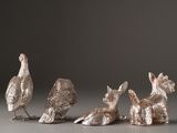 four silver figurines of animals sitting on a gray surface
