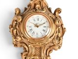 une horloge dorée sur un mur blanc, avec un fond blanc