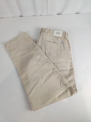 un pantalon beige posé sur une surface blanche, avec un fond blanc