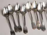 six silver spoons are lined up in a row on a table