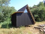 un petit bâtiment noir au toit en pente, situé dans un champ