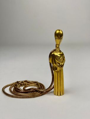 a gold figurine with a chain around it on a white surface