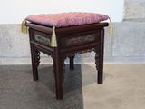 a small wooden stool with a pink cushion on it