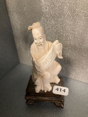 une petite statue représentant un homme assis sur un socle en bois