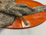 a sculpture of a bird sitting on a wooden plate