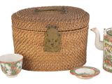 un panier en osier contenant une théière, des tasses et une théière
