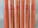 un lot de cinq livres rouges posés sur une surface grise