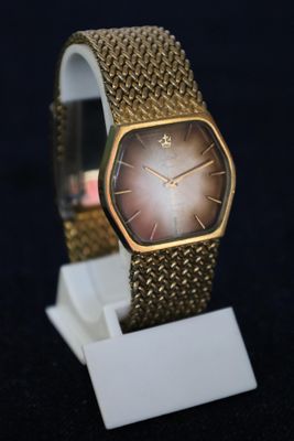 a gold watch on a white stand on a black background