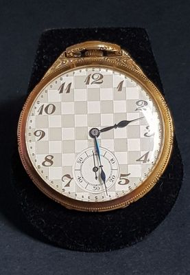 a close up of a gold watch on a black surface