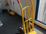 un diable jaune avec une poignée rouge, près d'une fenêtre