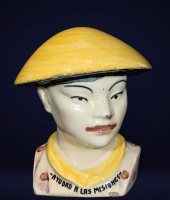 une figurine en céramique représentant un garçon coiffé d'un chapeau jaune
