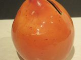 un petit vase orange posé sur une table blanche