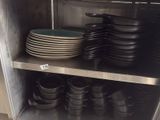 many plates and pans stacked on a shelf in the kitchen