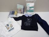 des vêtements et des couches pour bébé garçon disposés sur une table