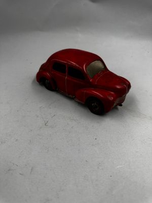 une petite voiture rouge posée sur une surface blanche
