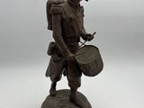 statue of a man with a drum and a hat on a white surface