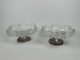 une paire de bols en verre transparent posés sur des socles métalliques, sur fond blanc