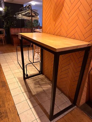 a long table with two stools next to a brick wall