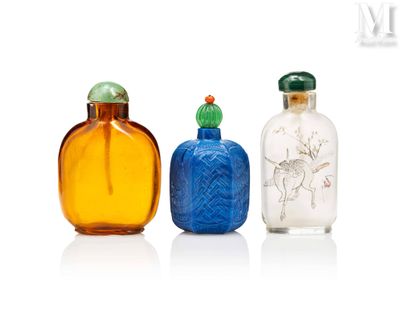 trois flacons à tabac en verre posés les uns à côté des autres sur une surface blanche