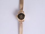 an image of a gold wrist watch with a black face on a white surface