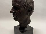 un buste en bronze représentant la tête d'un homme, posé sur un socle noir