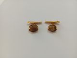 a pair of gold tone cufflinks with a brown stone