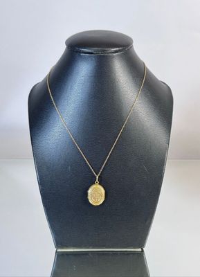 a gold necklace with a coin on a mannequin neck