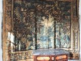 une grande tapisserie accrochée au mur, à côté d'une commode