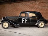 a old black car parked in front of a brick wall