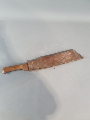 un couteau en bois posé sur une surface blanche, sur laquelle se dessine son ombre
