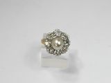 une photo d'une bague en perle blanche et diamants posée sur une surface blanche