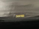 the back of a black purse with a gold label on it