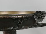 a bronze bowl with a woman holding a flower on it