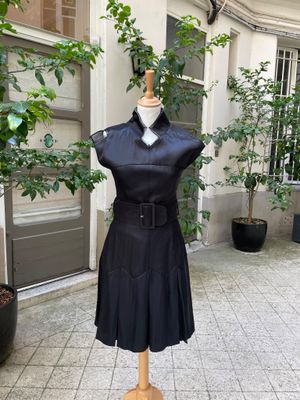 une robe noire posée sur un mannequin dans une cour