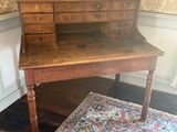 an old wooden desk with drawers and a rug on a wooden floor