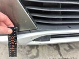 a person measuring the front of a car ' s grille with a ruler