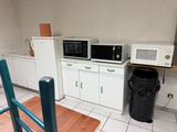 deux micro-ondes et une poubelle dans la cuisine