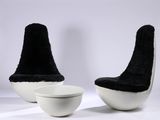 une paire de chaises noires et blanches et un bol posés sur une surface blanche